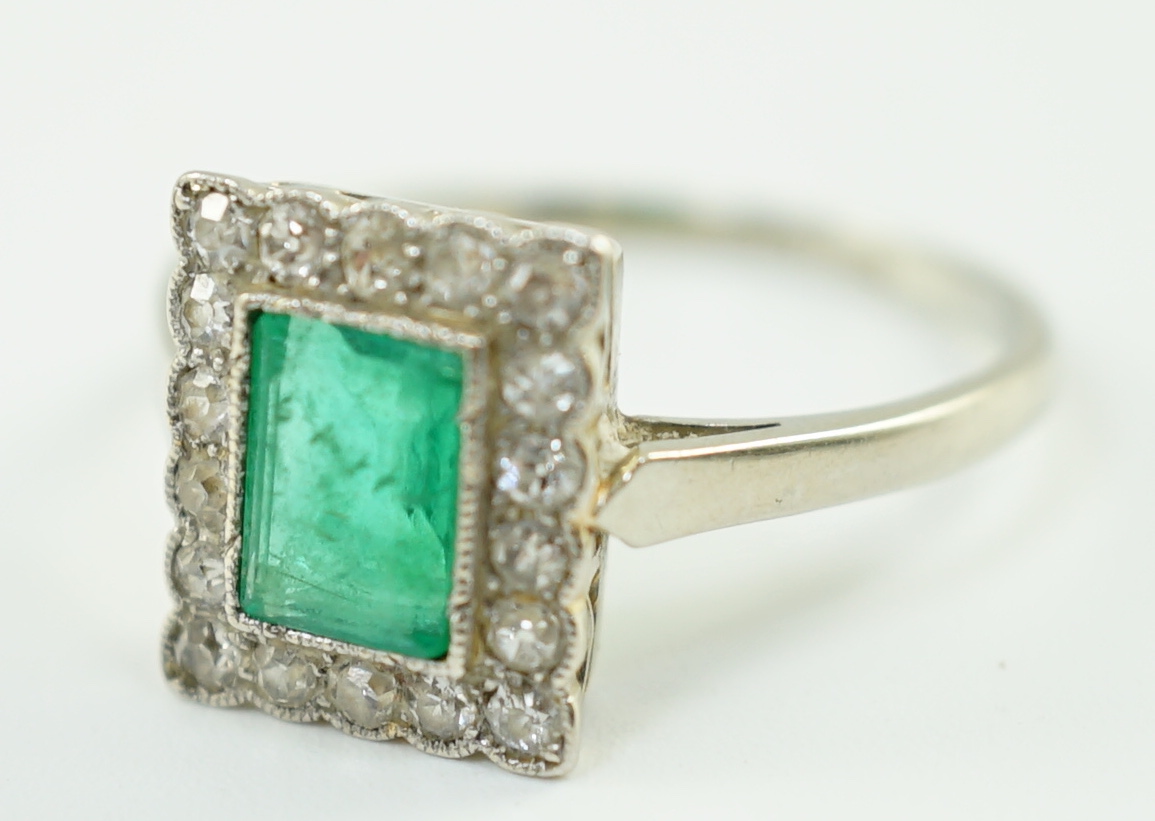 A 1920's 18ct white gold and platinum, emerald and millegrain set diamond rectangular cluster ring